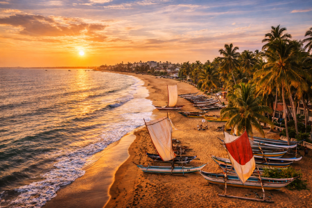 Traditional fishing boats on Negombo beach at sunset in Sri Lanka
