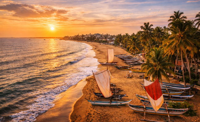 Traditional fishing boats on Negombo beach at sunset in Sri Lanka